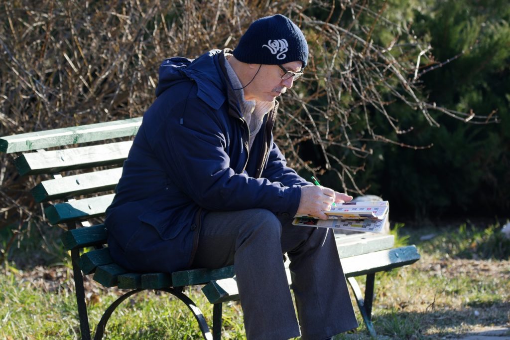 man sitting in the park working a crossword puzzle