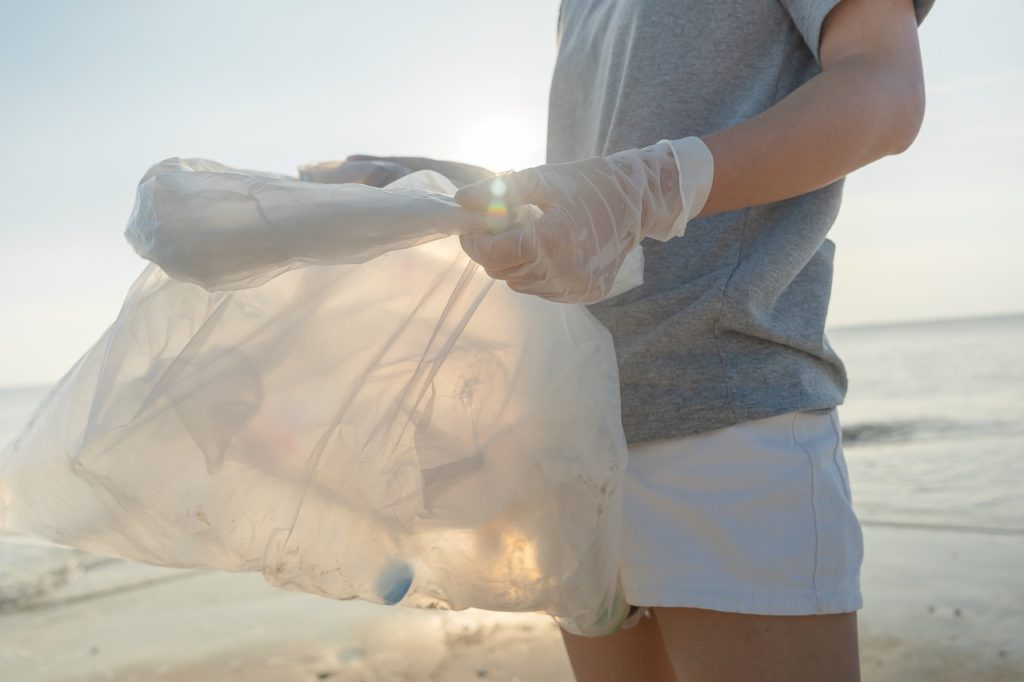 person volunteering by picking up trash on beach